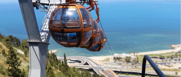 תאי הרכבל הכדוריים של חיפה מעל הכביש והחוף, על רקע הים